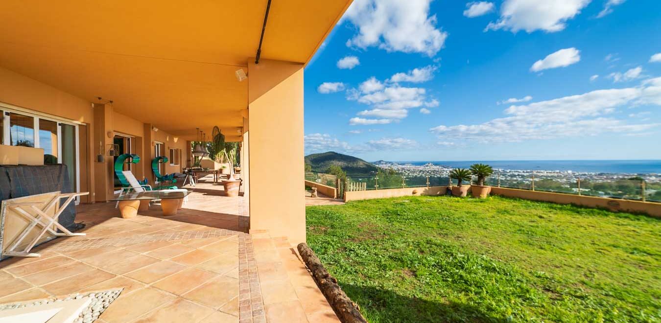 Amplia terraza de una villa de lujo en Ibiza con vistas panorámicas al mar Mediterráneo y un paisaje verde y exuberante