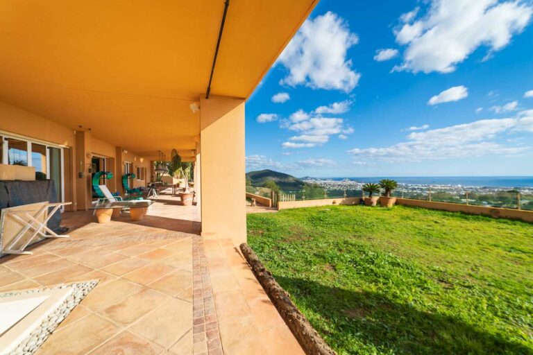 Spacious terrace of a luxury Ibiza villa with panoramic views of the Mediterranean Sea and lush green landscape