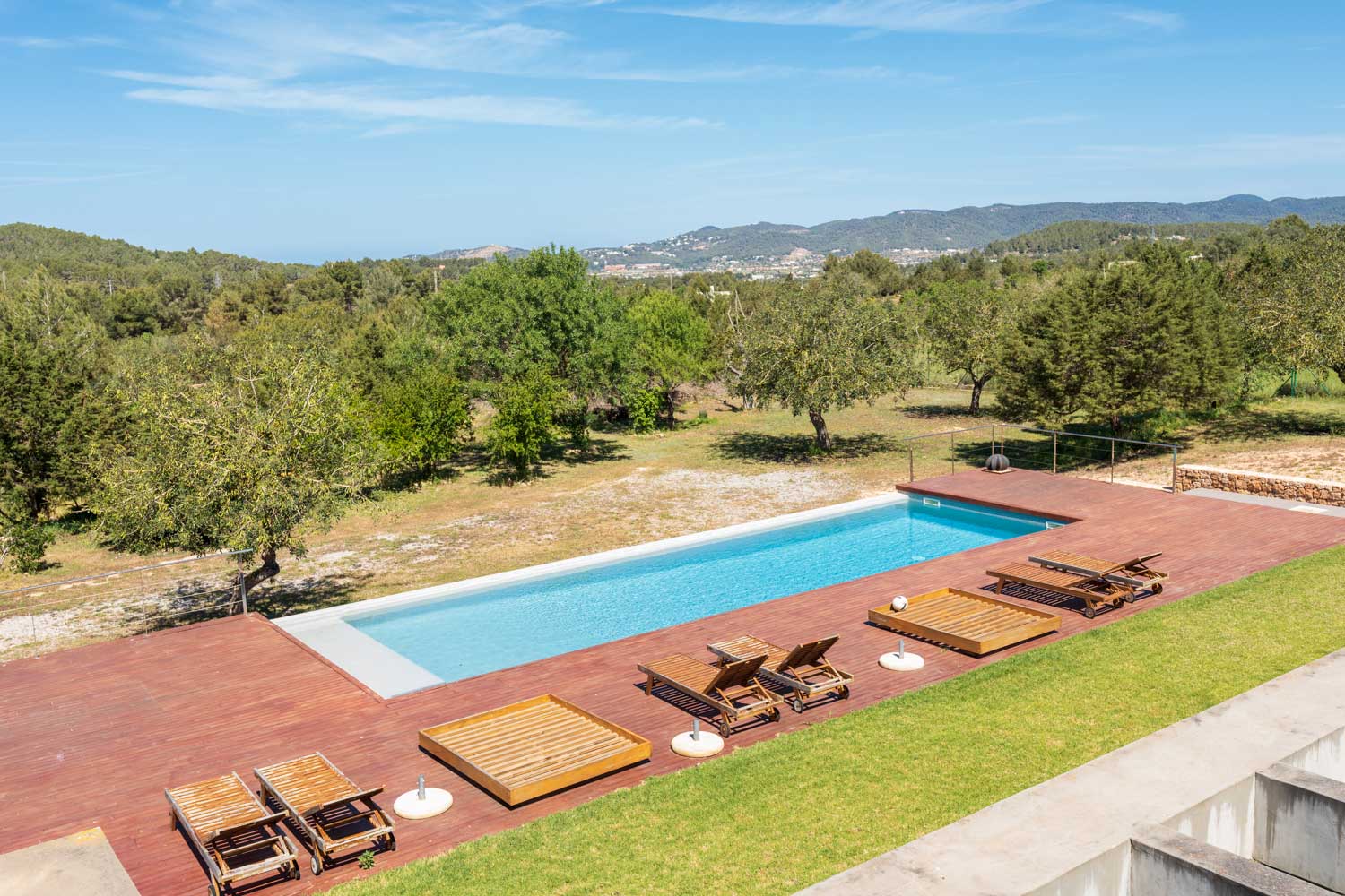 Moderna villa blanca con piscina infinita en Benimussa, Ibiza, que presenta una amplia terraza y un exuberante jardín